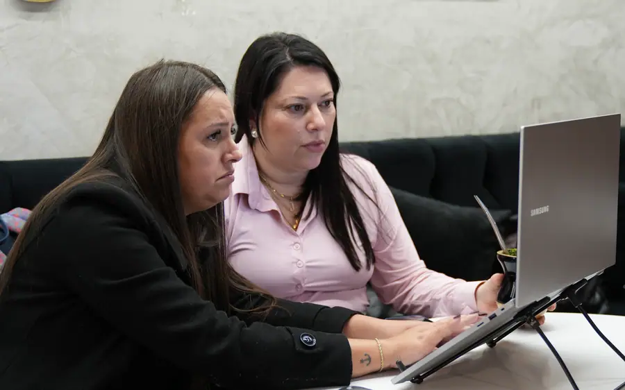 Duas mulheres revisando o trabalho no notebook, sob a marca da mentoria
